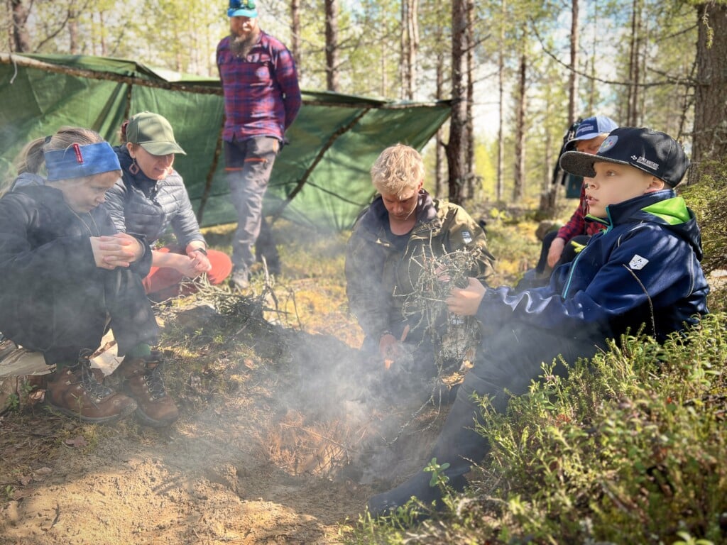 Participants practise fire-making during an overnight wilderness survival challenge in Ruka–Kuusamo.